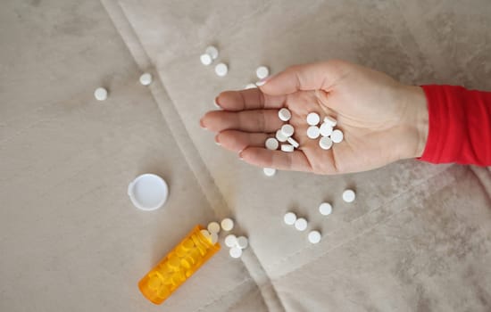 Female hand with white scattered pills. Antidepressants and suicide risk concept