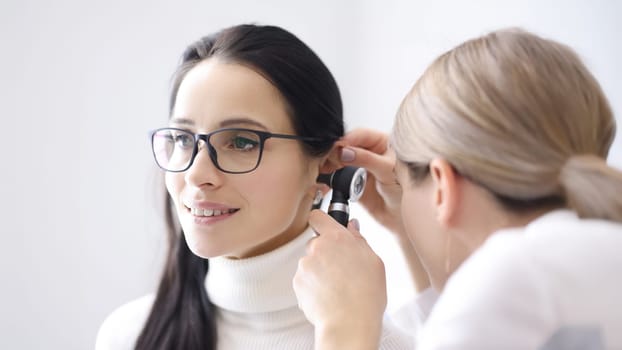 Doctor conducts examinations of ear area for woman. Acoustic neuritis concept