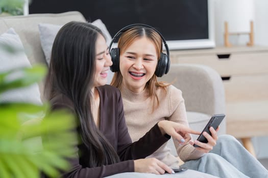 Happy lesbian couple sitting together in a cozy living room, sharing a joyful moment and enjoying each other's company.