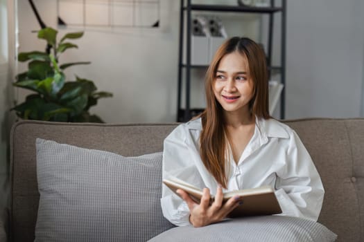 A woman sits comfortably on a couch, reading a book in the morning light, creating a serene and cozy atmosphere.