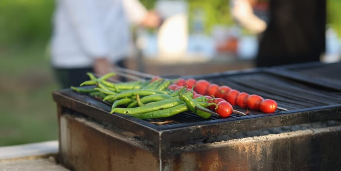 Cook prepares green peppers and grilled tomatoes. Recipes for cooking vegetables on charcoal concept