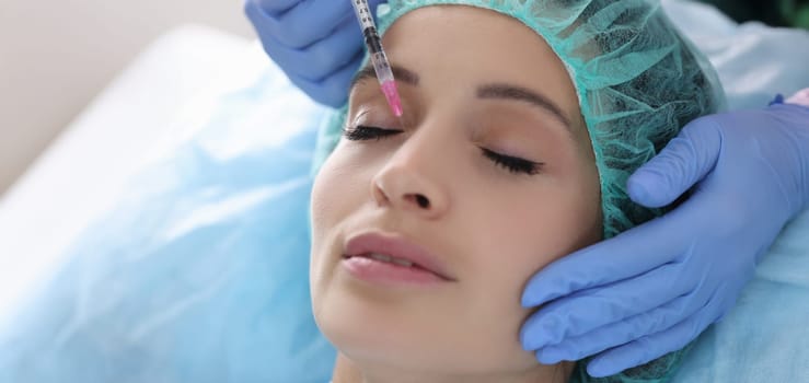 Beautician gives woman rejuvenating injection into skin of face. Restoration of epidermis of skin in cosmetology concept