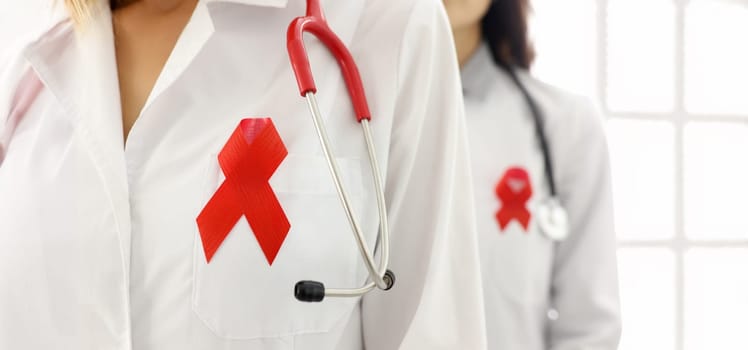 White doctor coat on chest with red ribbon. World aids day concept