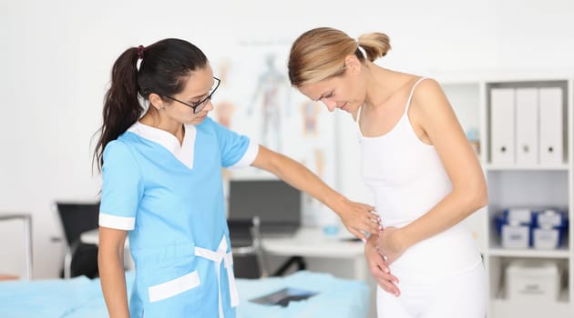 Doctor provides medical assistance to woman with abdominal pain. Pain syndromes in the intestinal area concept