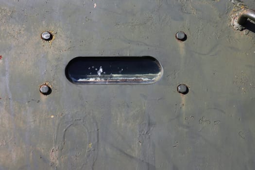 Close up view of the window handle of an old military vehicle.