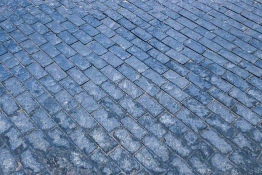 Fragment of an old square with blue paving stones.