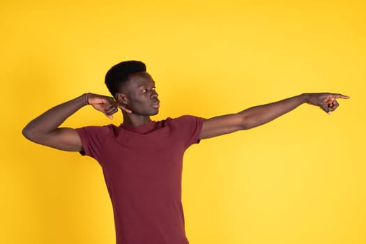 A man in a red shirt is pointing to the right. The image has a bright yellow background, which creates a cheerful and energetic mood