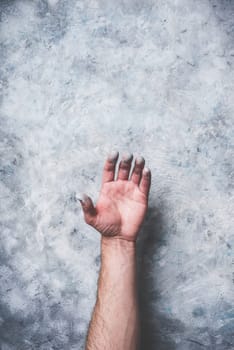 Man hand covered with paint on gray concrete wall background