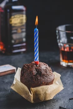 Chocolate muffin with birthday candle on dark concrete background