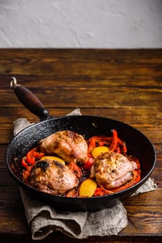 Chicken thighs baked with red bell peppers, rosemary and lemon in cast iron skillet.