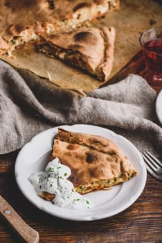 Slice of cabbage pie with sour cream sauce on white plate