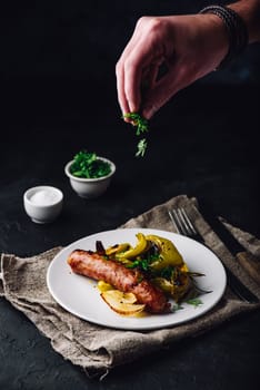 Pork sausage baked with bell peppers, onions and different herbs on white plate