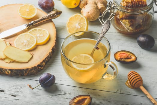 Cup of tea with lemon, honey and ginger over wooden surface