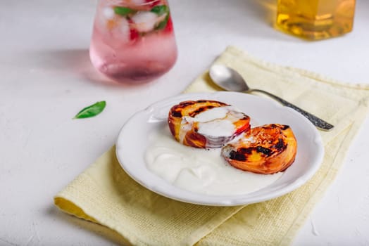 Served Oven Roasted Peaches with Honey and Whipped Heavy Cream on White Plate and Glass of Raspberry, Mint Mocktail