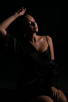 woman in black nightwear poses in the shadow of a room