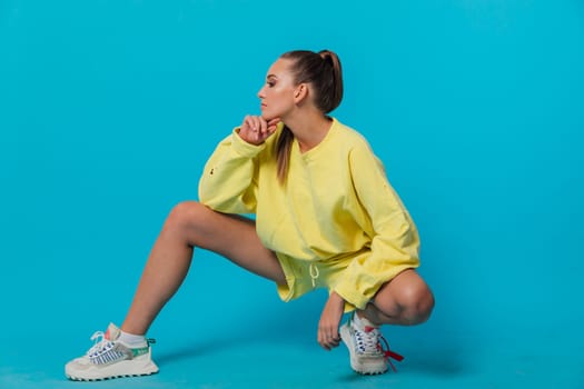 a woman in a yellow suit sits against blue wall