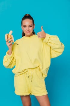 a woman in yellow clothes with a banana in her hand shows a class