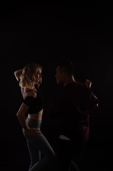 a man and a woman couple dance in dark studio room