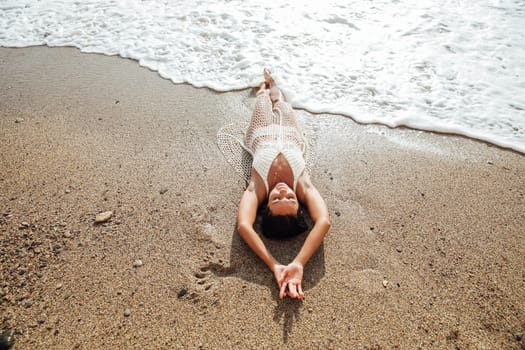 a woman in clothes in a net lies on the seashore rest on the beach