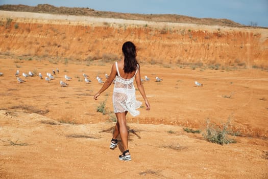 a woman in white clothes looks at birds in a sand quarry