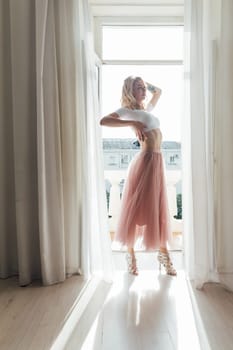 a woman in a pink skirt stands at the door of the balcony in the room