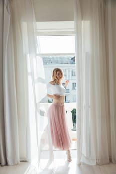 a woman in a pink skirt stands at the door of the balcony in the room