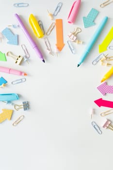 Top view of bright school supplies with blank paper for layout or text. Vertical photo