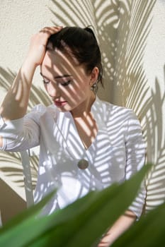 beautiful woman sitting in the shade of a plant in a room