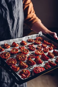 Baking Sheet Full of Freshly Cooked Sun Dried Tomatoes with Thyme in a Chefs Hands