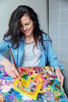 a woman artist draws with brush and paints on a palette of colors