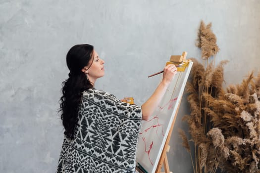 a woman artist paints a picture on an easel in an art studio