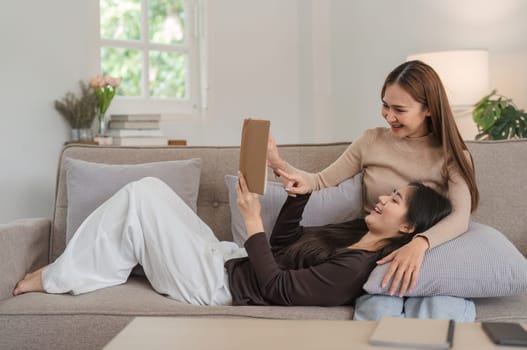 A loving lesbian and LGBT couple sitting together in a modern living room, sharing a joyful moment and enjoying each other's company.