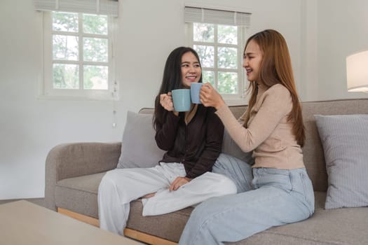 A loving lesbian couple enjoying coffee together on a comfortable sofa in a bright, modern living room.