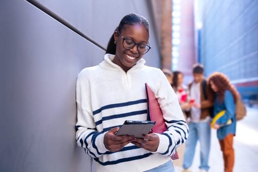 Young smiling student with notebook in hand uses social networks with smartphone applications and wireless technology outdoors.