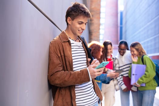 Young smiling student with notebook in hand uses social networks with smartphone applications and wireless technology outdoors.