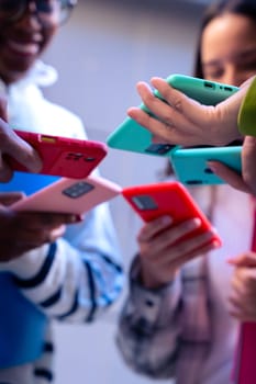 Vertical portrait unrecognizable group of friends using looking at their smartphones Multiracial teenagers browsing the internet with mobile phone on campus