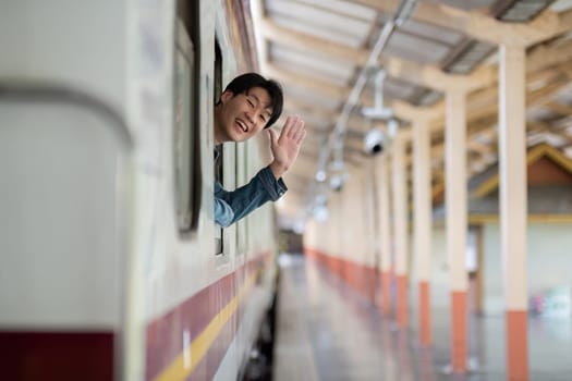 Young Man stands on the platform, waiting for the train at a modern train station, showcasing urban architecture and natural lighting.