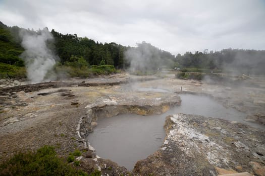 A large area of land is covered in steam and mud. The steam is coming from a volcano and the mud is from the lava. The scene is very dramatic and intense
