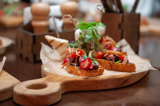 Tasty tomato Italian bruschetta on toasted slices of baguette with spice herbs and basil on a wooden board. Catering concept