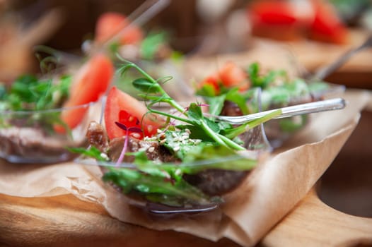 Tasty beef tongue meat with greens tomato sesame and sauce on a wooden board. Catering concept