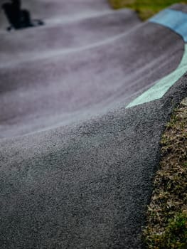 Pump track close up. Pumptrack curves with lines. Asphalted bicycle race track, pump track outdoors, kids playground. Racing speed track
