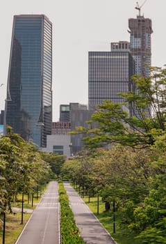 Bangkok, Thailand - 22 Jun, 2024 - The large urban park with trails for running and cycling serene atmosphere with Modern high-rise buildings and sky background. Space for text, Selective focus.