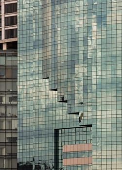 Bangkok, Thailand - 22 Jun, 2024 - Architectural exterior of modern office building facade with sky and clouds reflection in windows. Steel frame and glass windows architecture, Space for text, Selective focus.