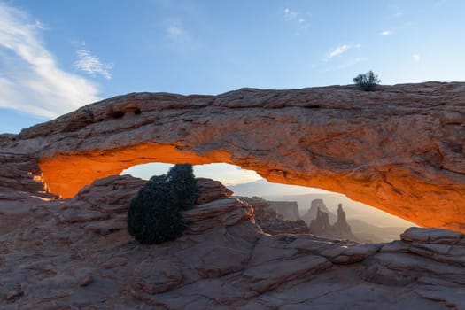 Breathtaking orange sunrise illuminating the under glow of Mesa Arch in Canyonlands National Park, Utah. Capturing the serene beauty of the desert landscape and natural rock formations - USA
