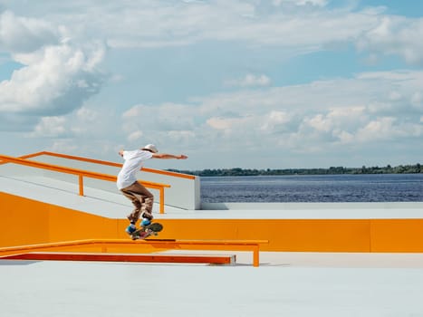 Caucasian Boy doing skateboard trick on rail in skatepark. Professional sportsman grinding on skateboard in outdoor park. Faceless unrecognizable young white skater doing Manual Grind trick on skate