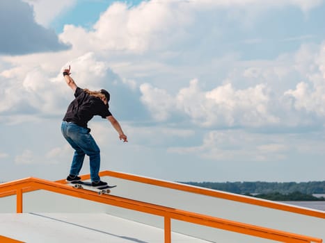 Caucasian Boy doing jump trick through rail on skateboard in skatepark. Professional skater sportsman jumping on skateboard in outdoor park. Faceless unrecognizable white skater doing trick on skate