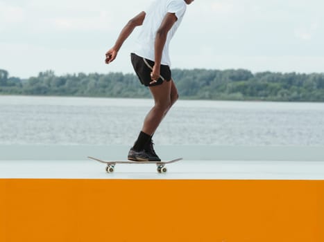 African man riding a skateboard. Faceless unrecognizable professional Afro skater in shorts riding on skate. Modern sport, subculture and skateboarding concept. Skate as hobby healthy lifestyle