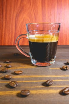Glass cup of Expresso on a wooden table, decorated with coffee beans.