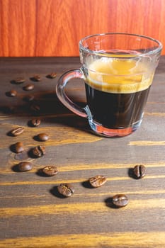Glass cup of Expresso on a wooden table, decorated with coffee beans.