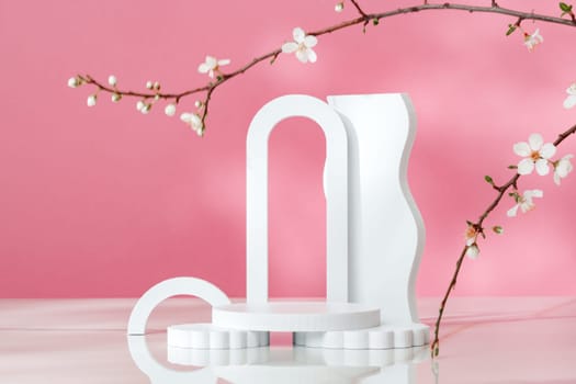 Decorative podiums and blooming branches on pink background with shadows copy space